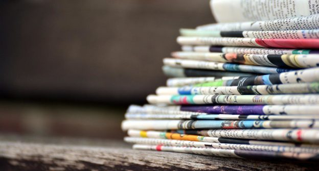 Newspapers stacked on a bench